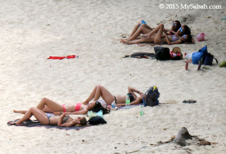 tourists sunbathe on Pulau Manukan