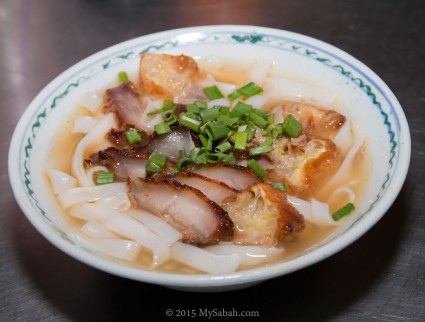 Kueh Teow noodle soup topped with deep-fried pork and sliced Chinese fritters