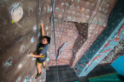 girl hanging at rock wall