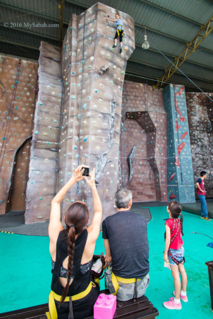 girl reaching the top of rock wall