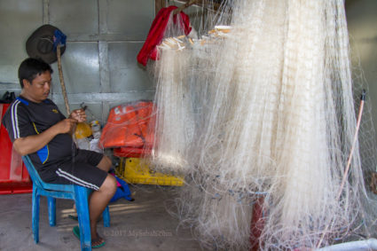 A fisherman repairing his fishing net