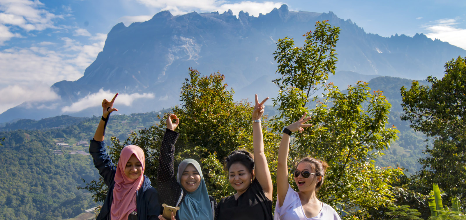 Four girls taking group photo with Mount Kinabalu
