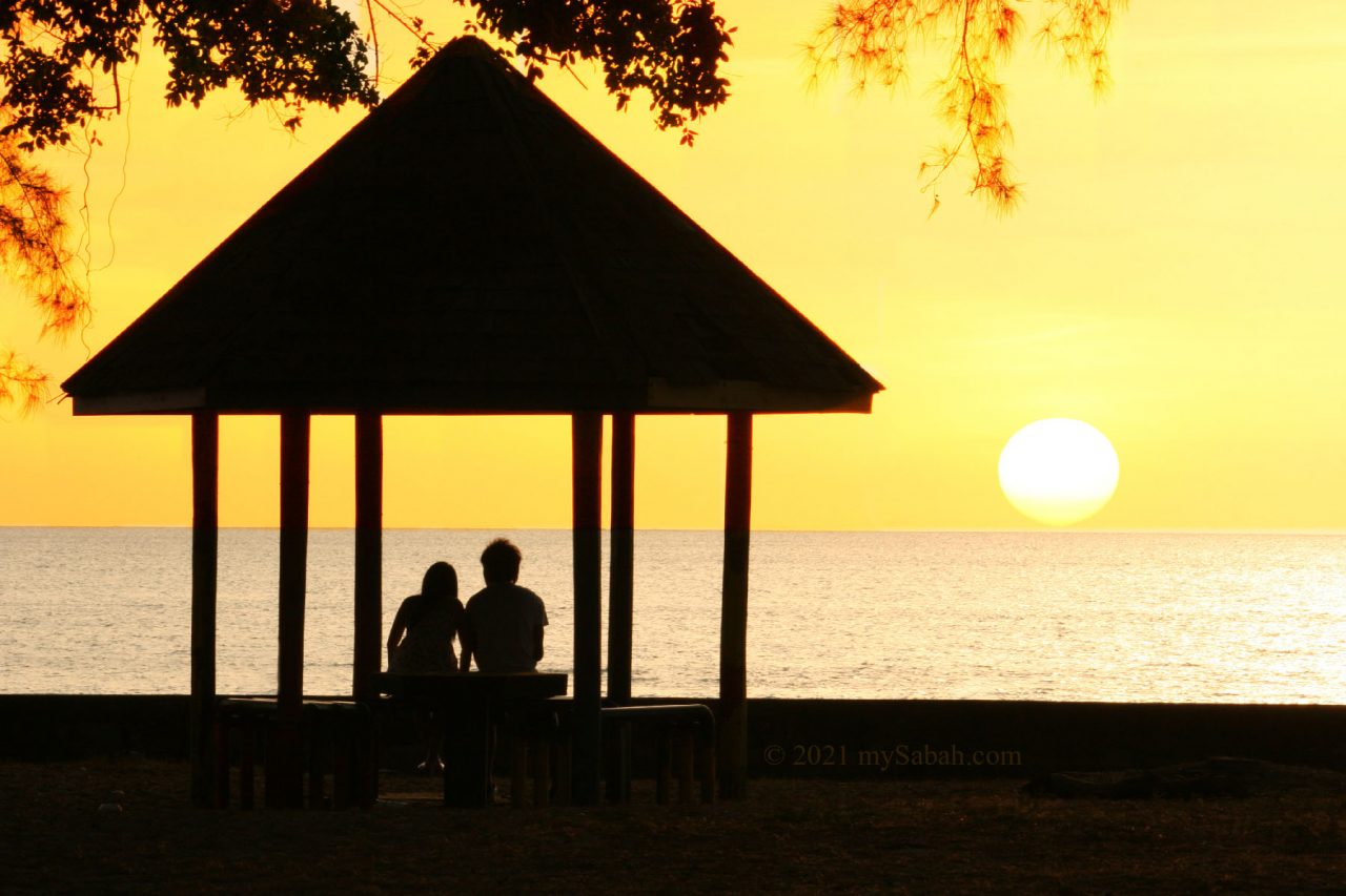 Couples looking at sunset of Tanjung Aru Beach from a gazebo