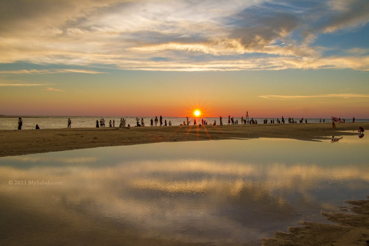 Tourists watching sunset at Dalit Beach, where Mengkabong River meets the sea