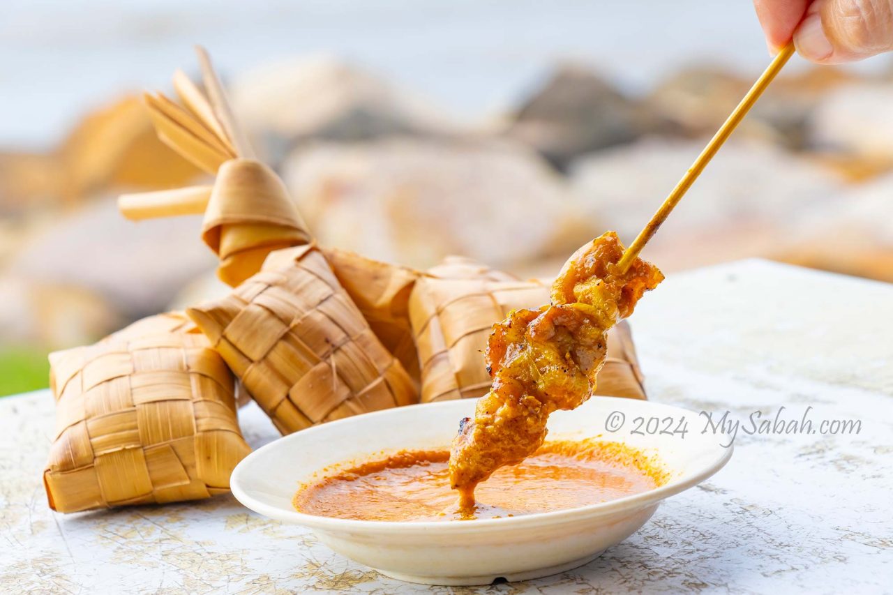 Dipping satay into peanut sauce