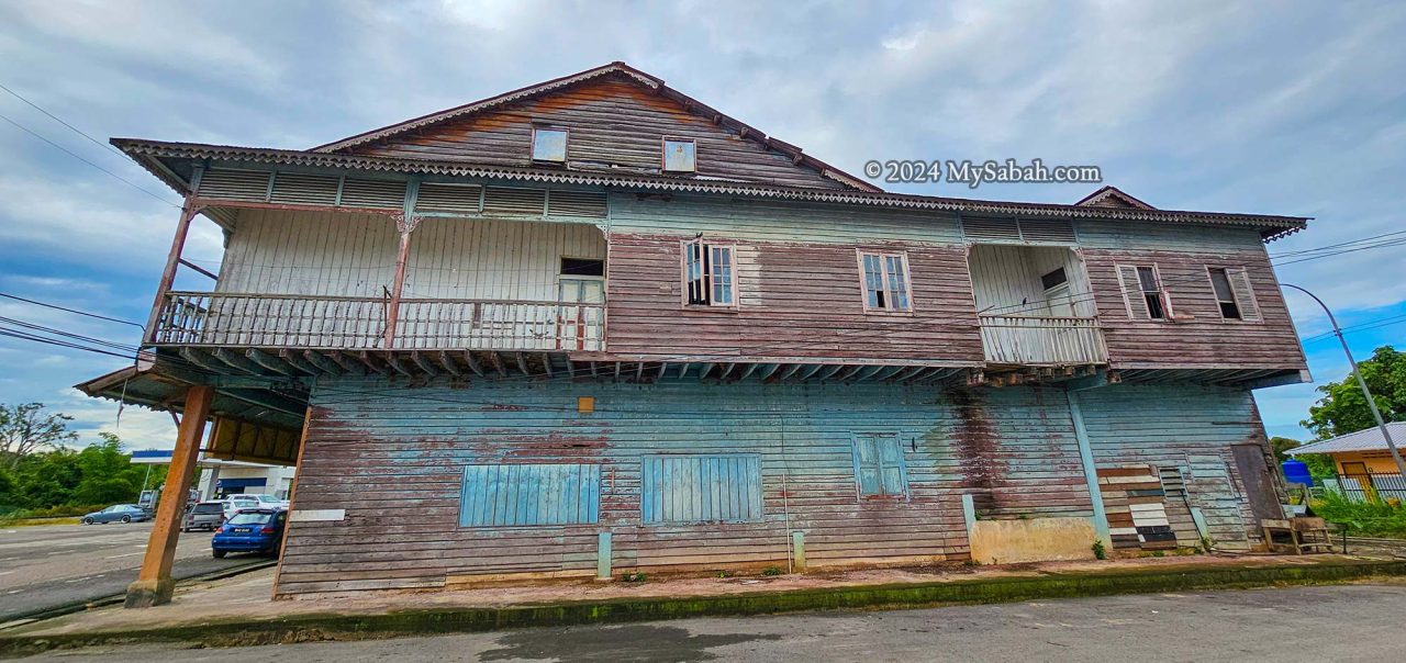 Dilapidated balconies decorated with louvered panels and small British Victorian brackets.