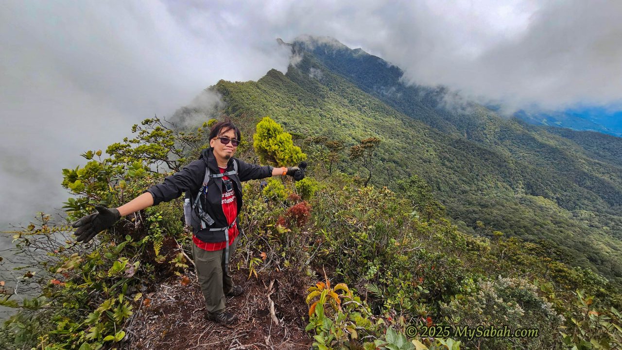 Climber spreads his arms on top of a mountain