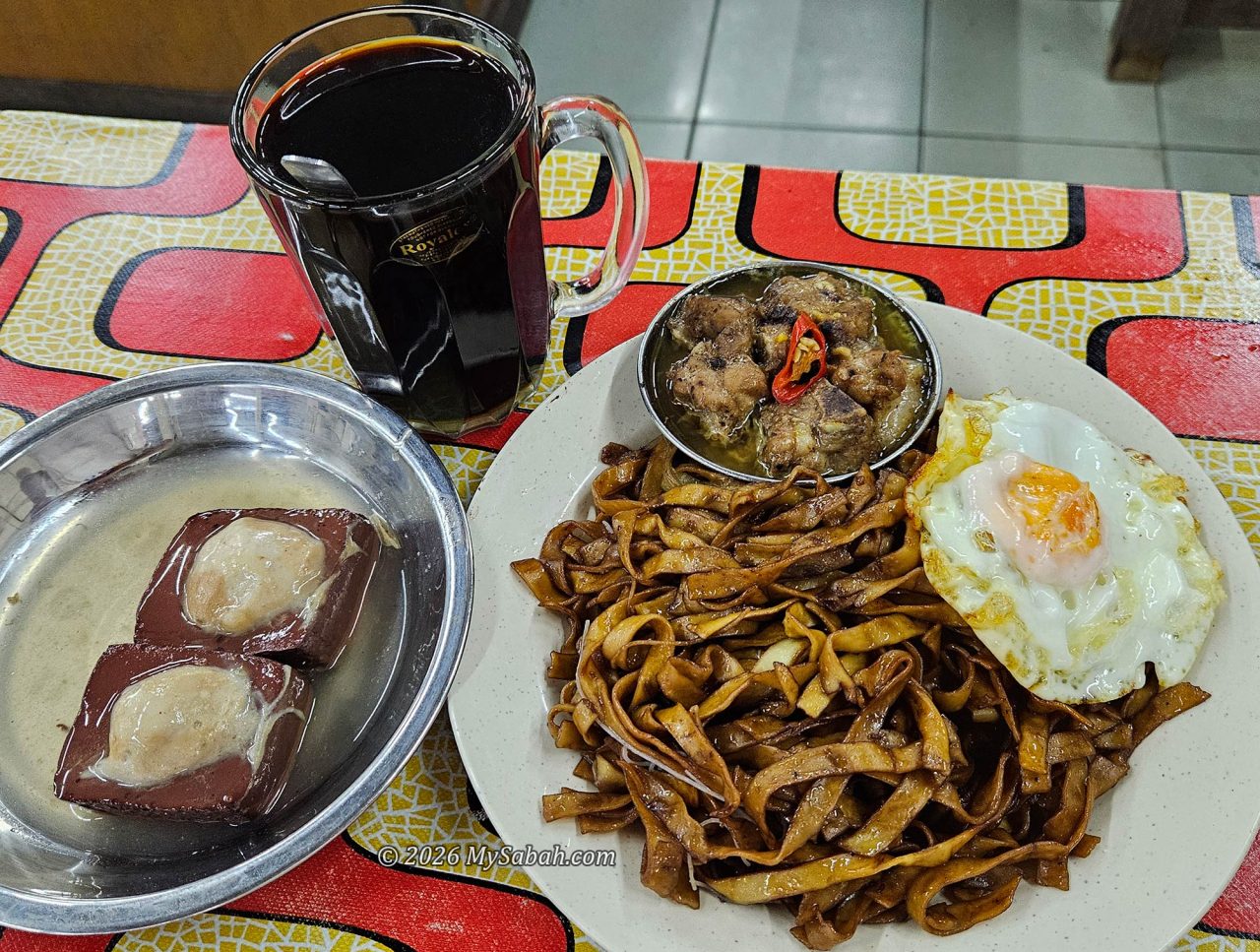 Typical Kudat breakfast: flat noodles, dim sum, fried egg, stuffed tofu, and coffee.